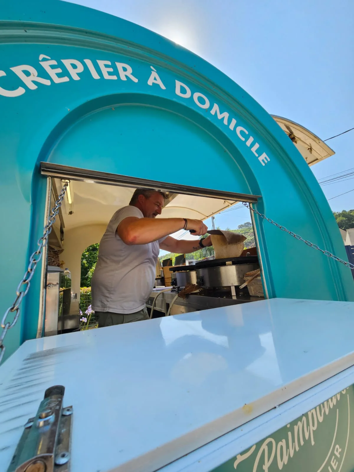 Anthony préparant des galettes dans sa remorque turquoise